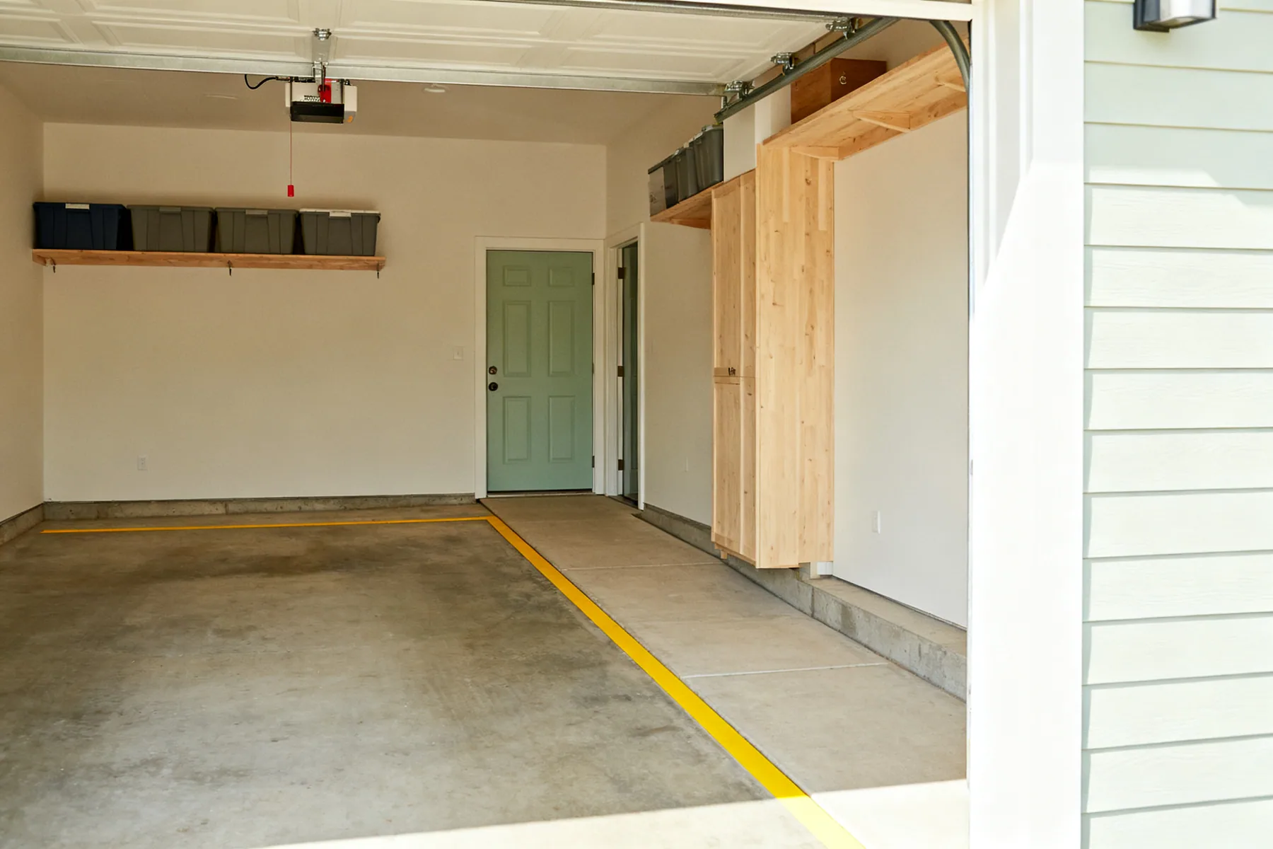 The floor marked out as circulation, not storage A garage floor with the car parking bay outlined in yellow floor tape and a marked clear walkway running down one side, with all storage kept on the walls and overhead