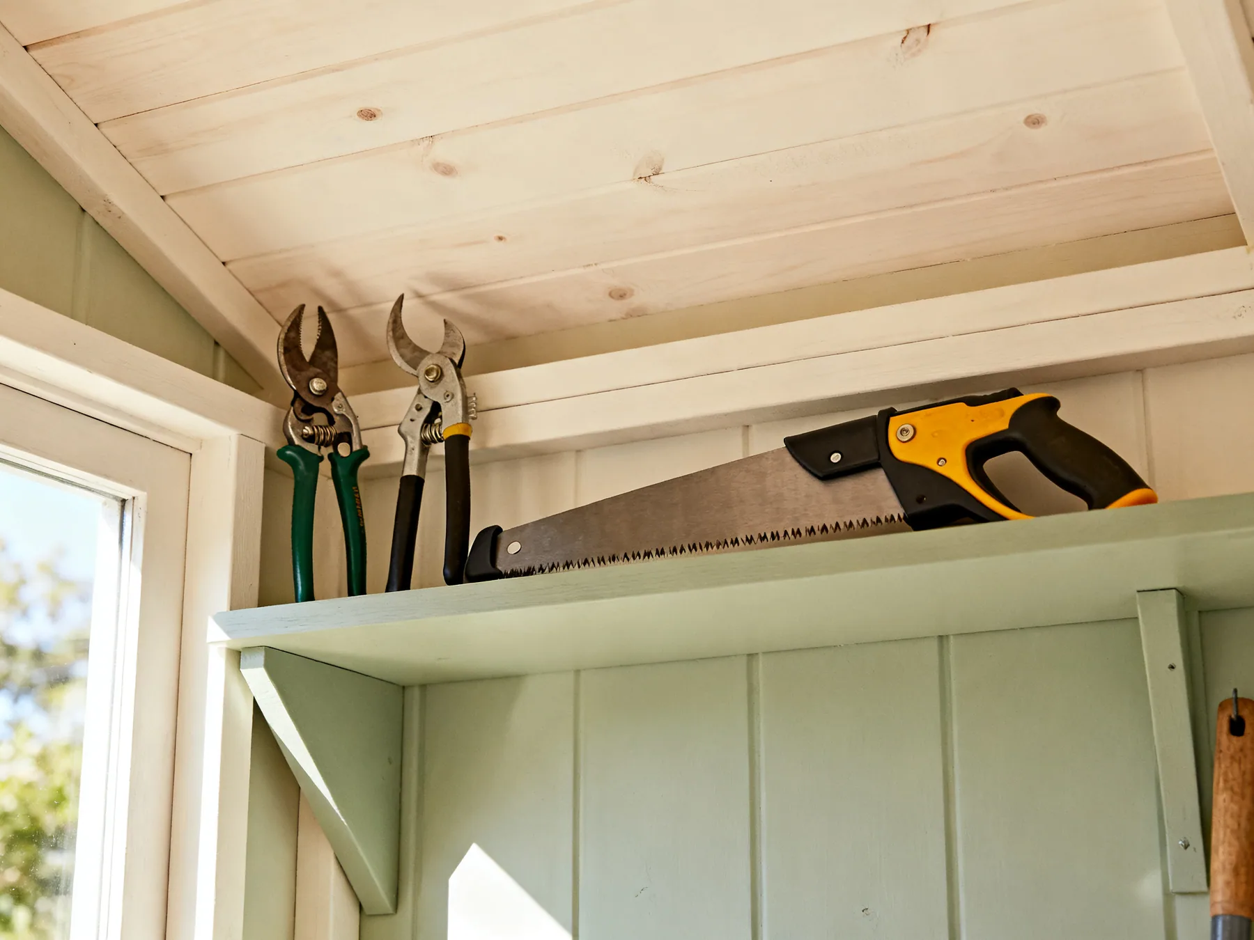 Guards on, and stored high Garden shears and a pruning saw with blade guards fitted, stored on a high shed shelf above child reach