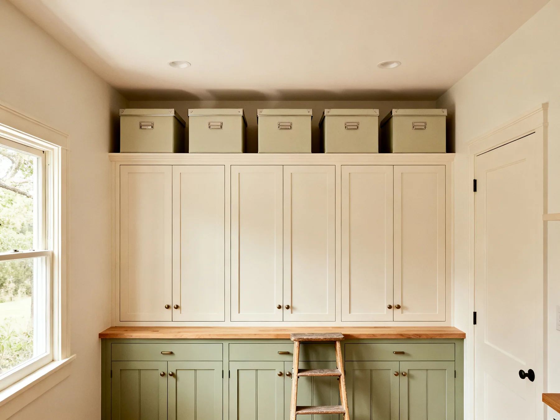 The 300 to 450mm above the wall units The gap between the top of kitchen wall cabinets and the ceiling filled with a row of five matching lidded boxes, with a step stool below