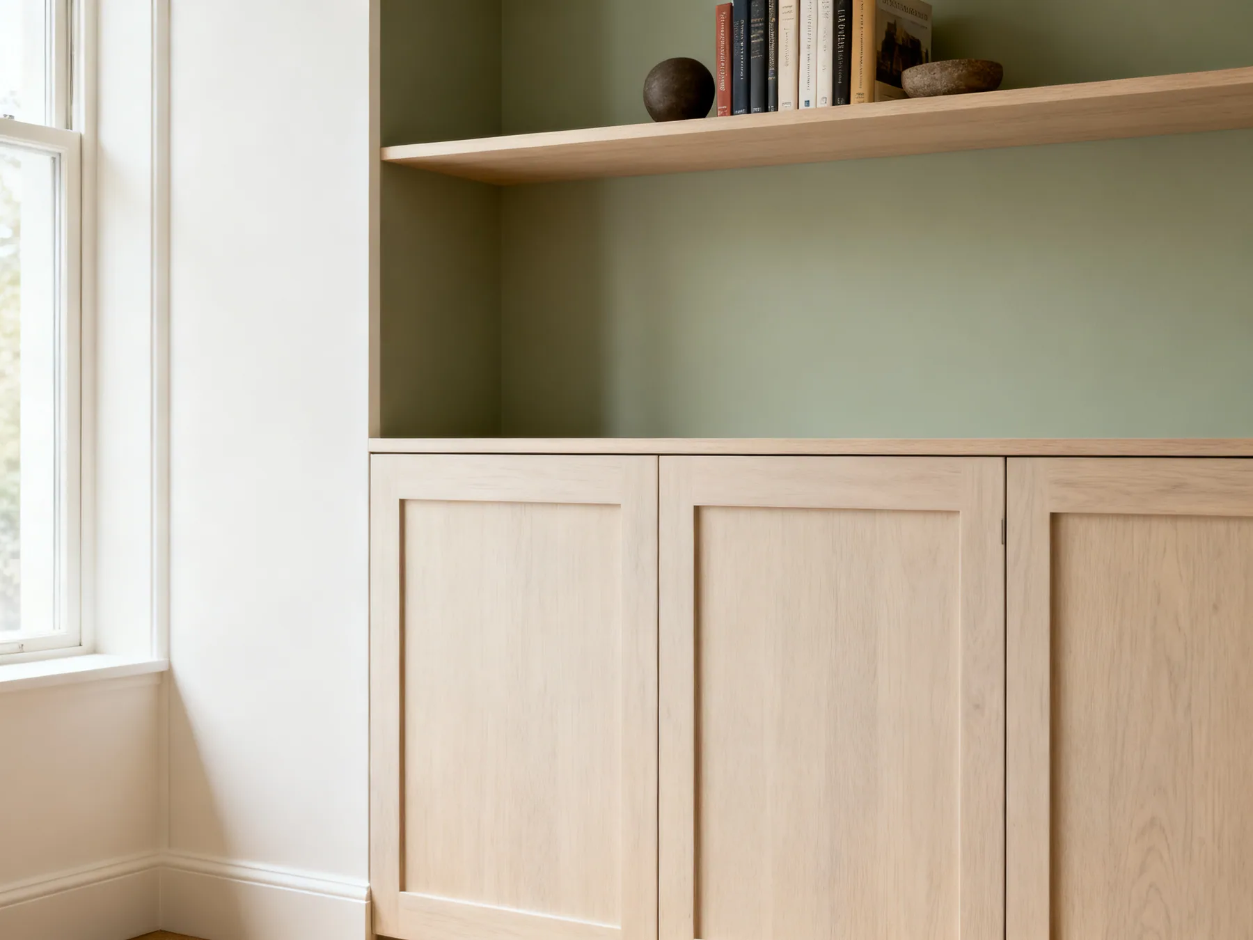 Closed below, open above A living room wall with closed cupboard doors below and open shelving above holding a small curated group of books and objects