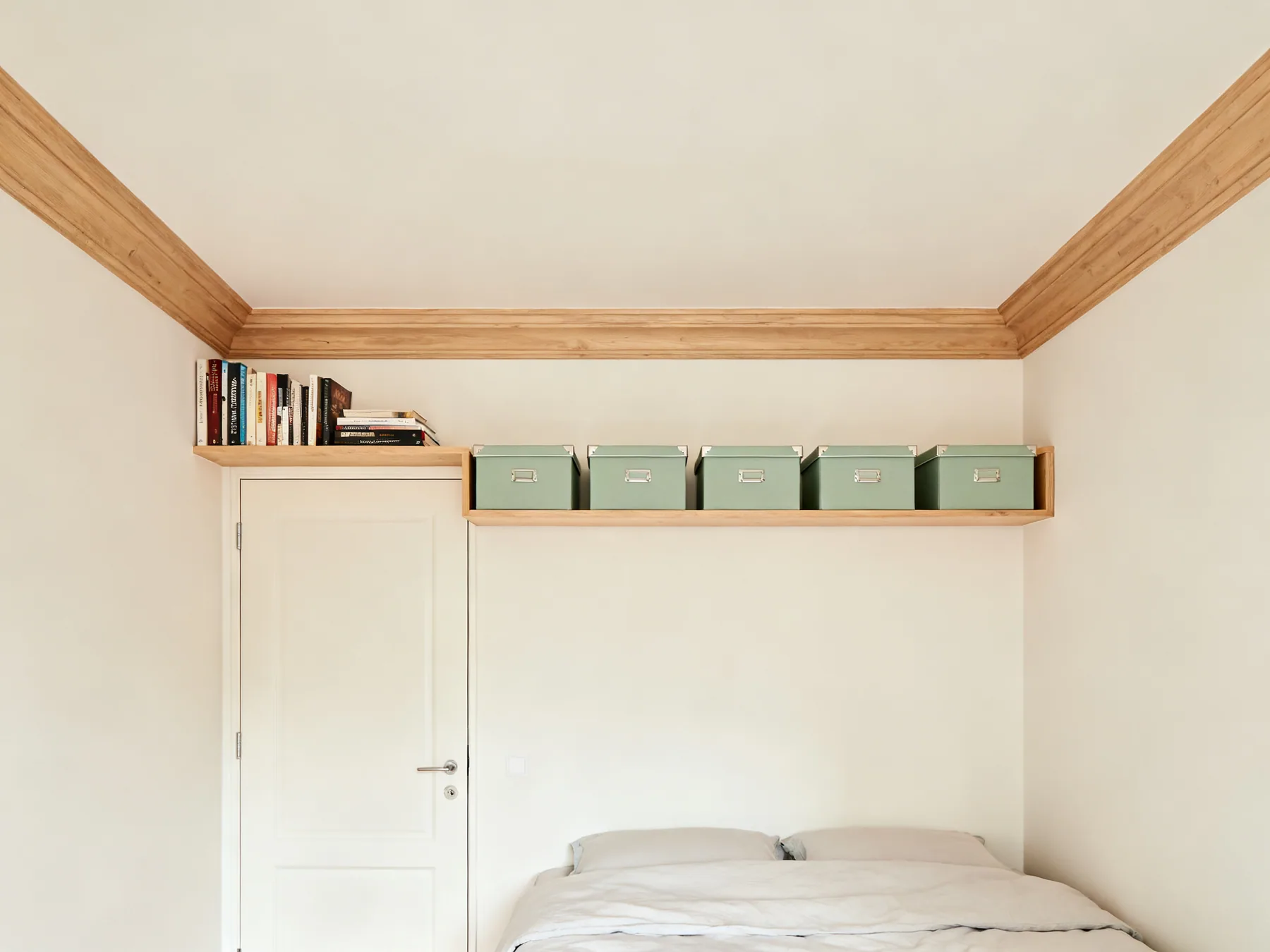 A high perimeter shelf at about 1.9m A single continuous shelf running around two walls of a small bedroom above door head height, holding books and a row of matching lidded boxes